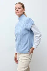 Chaleco de tejido de punto color crudo, con diseño de ochos verticales y cuello redondo. Presenta un corte holgado y terminaciones acanaladas en cuello, sisas y ruedo.