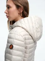 Campera acolchada ultraligera de color blanco, con capucha, cierre frontal de cremallera y bolsillos laterales. Diseño entallado con acabado resistente al viento y la humedad.