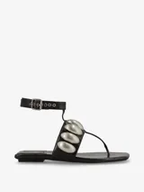 Sandalia negra de punta cuadrada con tira adornada con detalles plateados y correa ajustable al tobillo con hebilla.