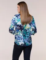 Blusa de gasa estampada de la marca Zac & Rachel, con diseño floral en tonos azul, celeste y verde sobre base blanca. Presenta escote en V con abertura y botones frontales, y mangas largas de largo regulable con presilla.