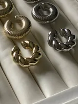 Aro trepador plateado con forma de "C" y diseño trenzado.