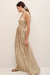 Vestido largo dorado de poliéster metalizado con tirantes finos, escote en V y corte fluido.