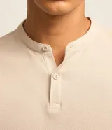 Chomba celeste de corte slim, confeccionada en tejido piquet texturizado de algodón, con cuello mao y cierre frontal parcial con botones.