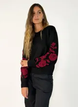Sweater negro de punto con cuello redondo y mangas largas, destacando por un bordado floral en color bordó que recorre las mangas.