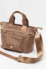 Cartera negra de nylon con diseño compacto y funcional. Cuenta con asas cortas y correa regulable desmontable para llevar al hombro o cruzada, además de múltiples bolsillos con cierre y detalles dorados.