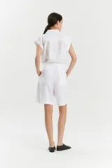 Bermuda blanca de lino de corte recto y estilo sastrero, con bolsillos laterales y cartera de botones oculta.