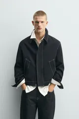Sobrecamisa de corte regular fit color negro con pespuntes en contraste blancos. Presenta cuello solapa, mangas largas con puños abotonados, bolsillos frontales de vivo y cierre de cremallera oculta por solapa con botones.