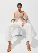 Jeans blancos de tiro medio con diseño wide leg y bordado de flores tono sobre tono en las perneras. Cuentan con diseño clásico de cinco bolsillos, trabillas y cierre frontal de botón y cremallera.