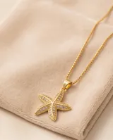 Collar de cadena fina eslabonada en color dorado con dije en forma de estrella de mar, cubierto de circones brillantes.