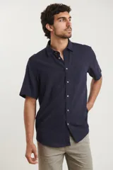 Camisa sport de manga corta, confeccionada en una mezcla de lino y algodón. Presenta cuello clásico, cierre frontal con botones de coco y un bolsillo aplicado en el pecho.