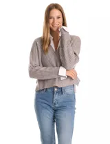 Buzo de tejido de punto acanalado color gris, con escote en V y lentejuelas incrustadas. Presenta un efecto combinado con cuello y puños de camisa blanca asomando por debajo.