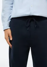 Pantalón tipo babucha de color azul oscuro, confeccionado con interior de felpa. Presenta cintura elástica con cordón de ajuste y puños acanalados en los tobillos.