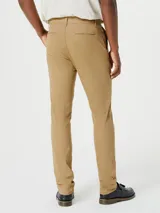Pantalón tipo chino de corte slim, color beige, con cierre de botón y cremallera, y bolsillos laterales.
