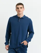 Remera de manga larga con cuello polo, confeccionada en tejido de punto canalé francés. Presenta abotonadura frontal con botones de madera y detalles a contratono en la cartera y el interior del cuello.