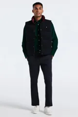 Chaleco reversible de pana, con cierre frontal de botones a presión y cuello alto. Presenta un diseño acolchado con logo bordado en el pecho.