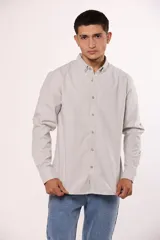 Camisa de manga larga en color gris, confeccionada en algodón, con cuello abotonado y cierre frontal de botones.