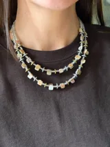 Collar corto de doble tira elaborado con cuentas de nácar teñido en tonos tierra, discos de hematita en acabado dorado y plateado, intercalados con mostacillas y detalles de acero quirúrgico.