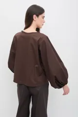 Blusa color marrón chocolate con mangas abullonadas de gran volumen y diseño estructurado.