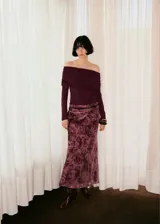 Jersey de punto fino color bordó, con diseño entallado, cuello drapeado estilo palabra de honor y mangas largas.