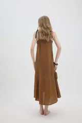 Vestido midi de lino color salmón, de corte amplio y silueta holgada. Presenta diseño con cortes irregulares y detalles de pasamanería en el escote y costuras. Cuenta con breteles dobles tipo cuerda y ruedo asimétrico.