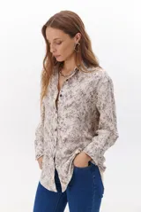 Camisa de corte holgado con estampado floral en tonos marrones y blancos, cuello clásico y cierre frontal con botones.