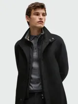 Abrigo corto negro de BOSS, confeccionado en lana y cachemira, con cuello alto, cierre abotonado y bolsillos laterales. Incluye chaleco interno desmontable con cierre.