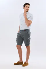 Bermuda cargo color azul marino, de gabardina con bolsillos laterales con solapa en las piernas y presillas para cinturón. Incluye cinturón de lona trenzada oscura con detalles en cuero sintético y hebilla metálica.