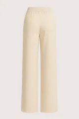 Pantalón de corte recto y tiro medio, confeccionado en tejido de punto color crema. Presenta cintura elástica con cordón ajustable y diseño holgado.