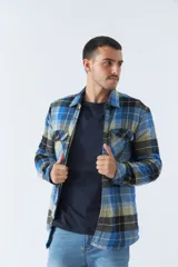 Sobrecamisa de algodón a cuadros color ladrillo, con interior de corderito, cierre con botones, bolsillos tipo cartera y logo en goma. El modelo usa talle M.