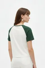 Remera al cuerpo con diseño raglán, color blanco en el torso y azul marino en las mangas cortas y el cuello. Cuenta con un estampado frontal de temática de tenis con las inscripciones "Portofino Tennis" y "Summer Italia".