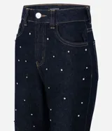 Pantalón de jean corte mom, color azul oscuro, con cintura alta y detalle de remaches metálicos distribuidos por toda la prenda. Cuenta con cierre frontal, botón y bolsillos funcionales.