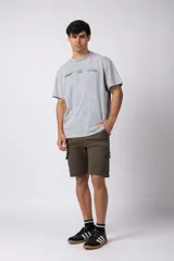 Bermuda cargo de gabardina con bolsillos laterales amplios con solapa y broche metálico. Presenta cintura con pasadores para cinturón y etiqueta tejida decorativa en uno de los bolsillos.