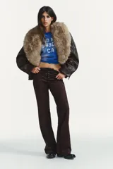 Pantalón de tiro bajo confeccionado en gamuza marrón, con diseño flare y detalle de lazada frontal. Presenta costuras marcadas y cierre lateral con cremallera.