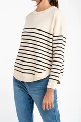 Sweater de punto con diseño a rayas horizontales negras sobre base color crema, cuello redondo, mangas largas y puños acanalados.