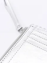 Billetera plateada rectangular con cierre de cremallera y correa de mano. Decorada con tachas redondas plateadas en los bordes.