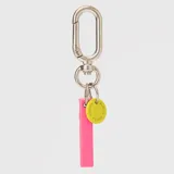 Llavero con dije en forma de letra A color rosado y pequeño dije circular amarillo con logo de la marca grabado. Incluye gancho metálico tipo mosquetón.