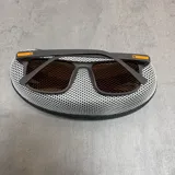 Lentes de sol con filtro UV 400 y armazón color naranja con detalle en la patilla.