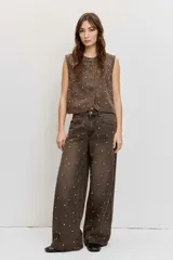 Chaleco de denim marrón con efecto acid wash y apliques de strass distribuidos por toda la prenda, sin mangas y con cierre frontal de botones.