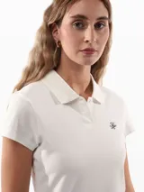 Chomba blanca de piqué de algodón regenerativo con corte slim, cuello tipo polo, cartera de dos botones, logo Tommy Hilfiger Script bordado en el pecho y bandera de Tommy Hilfiger bordada en la manga.