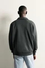 Sudadera polo de corte regular, confeccionada en tejido técnico interlock de algodón con elasticidad. Presenta cuello solapa, cierre frontal de cremallera y manga larga con puños acabados en rib.