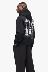 Canguro negro de mezcla de algodón de peso medio con interior cepillado suave. Cuenta con capucha de doble capa con cordón ajustable, hombros caídos, bolsillo canguro y puños y bajo acanalados. Presenta un estampado frontal de un león sentado con texto en blanco.