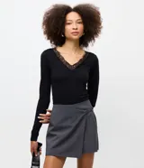 Body de manga larga color negro, con escote en V adornado con detalles de encaje. Presenta un diseño ajustado al cuerpo, confeccionado en una mezcla de algodón y elastano.