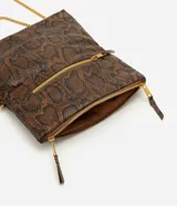 Cartera bandolera de tamaño mediano con estampado de piel de serpiente en tonos marrones y negros. Cuenta con asa de cadena dorada, solapa frontal y detalles de cierres metálicos con tiradores de cuero.