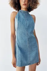 Vestido corto de denim con cuello halter, espalda descubierta y diseño de lavado combinado en tonos de azul.