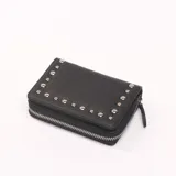 Billetera de cuero sintético color negro, con diseño rectangular y cierre perimetral. Presenta detalles de tachas metálicas plateadas en la solapa frontal.