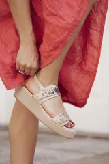 Sandalia de plataforma color beige claro, con dos tiras anchas con estampado de piel de serpiente (pitón) y hebillas metálicas.