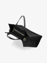 Cartera estructurada de gamuza color marrón oscuro, con doble asa de mano en cuero negro y correa regulable y desmontable en cuero negro con herrajes dorados.