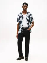 Camisa de hombre de corte regular con estampado de hojas en tonos azul y blanco sobre fondo negro. Tiene cuello cubano y manga corta.