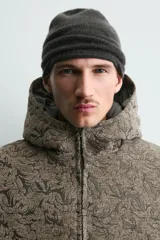 Cazadora acolchada de corte relajado con estampado jacquard. Presenta cuello subido con capucha, cierre frontal de cremallera, bolsillos frontales y puños con acabado elástico.