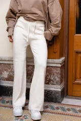 Pantalón de punto color beige, de corte wide leg y tiro alto, con cintura elástica ajustable mediante cordón del mismo material.
